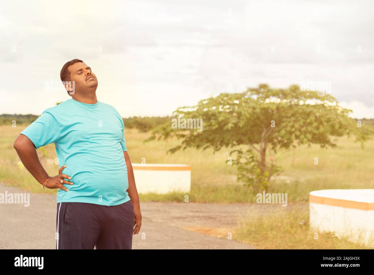 Stanco giovane uomo obesi holiding schiena durante il jogging - Concetto di uomo grasso fitness e uno stile di vita poco salutare. Foto Stock