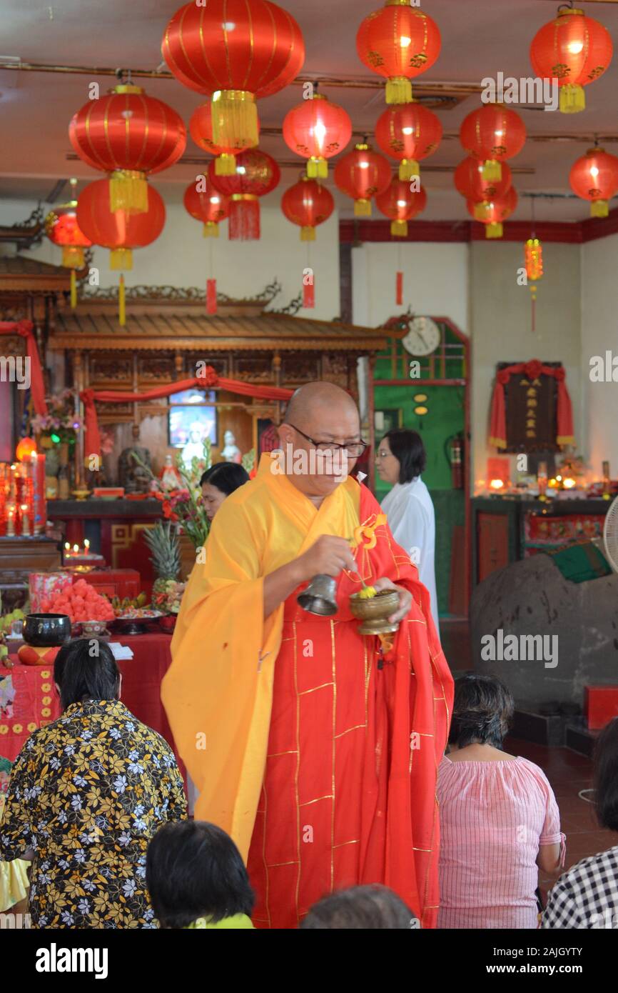 Un sacerdote buddista sta benedicendo alcune persone in un tempio prima della celebrazione del Capodanno cinese. Foto Stock