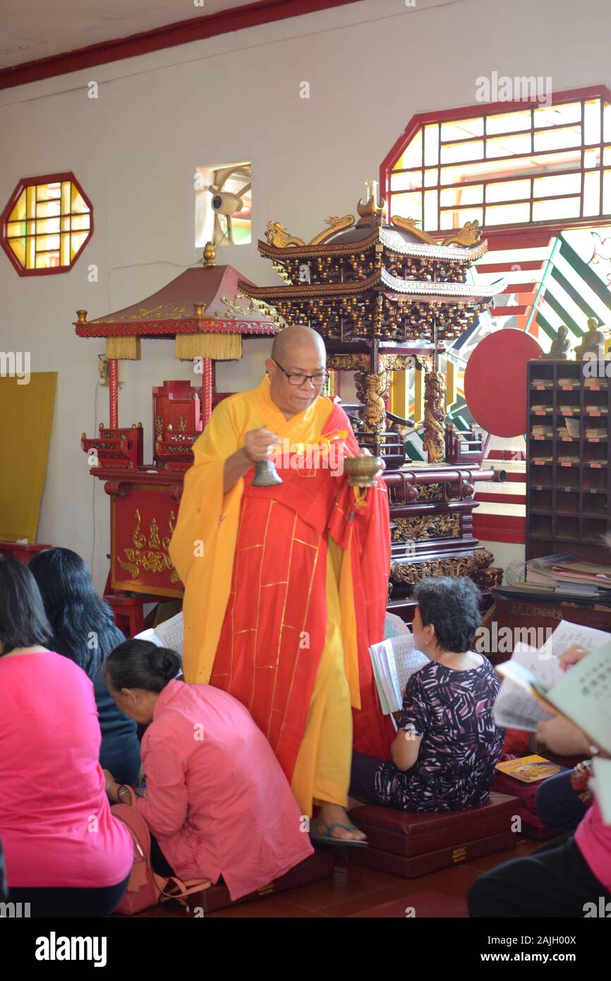 Un sacerdote buddista sta benedicendo alcune persone in un tempio prima della celebrazione del Capodanno cinese. Foto Stock
