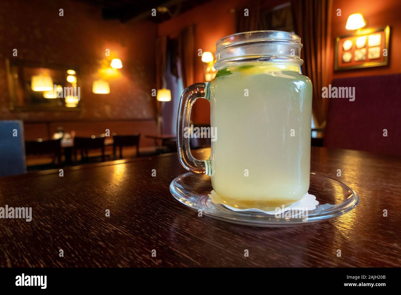 Bere caldo e rinfrescante tè allo zenzero con fetta di limone in un ristorante. Tazza di naturale tè alle erbe su un tavolo di legno, caldo inverno bere Foto Stock