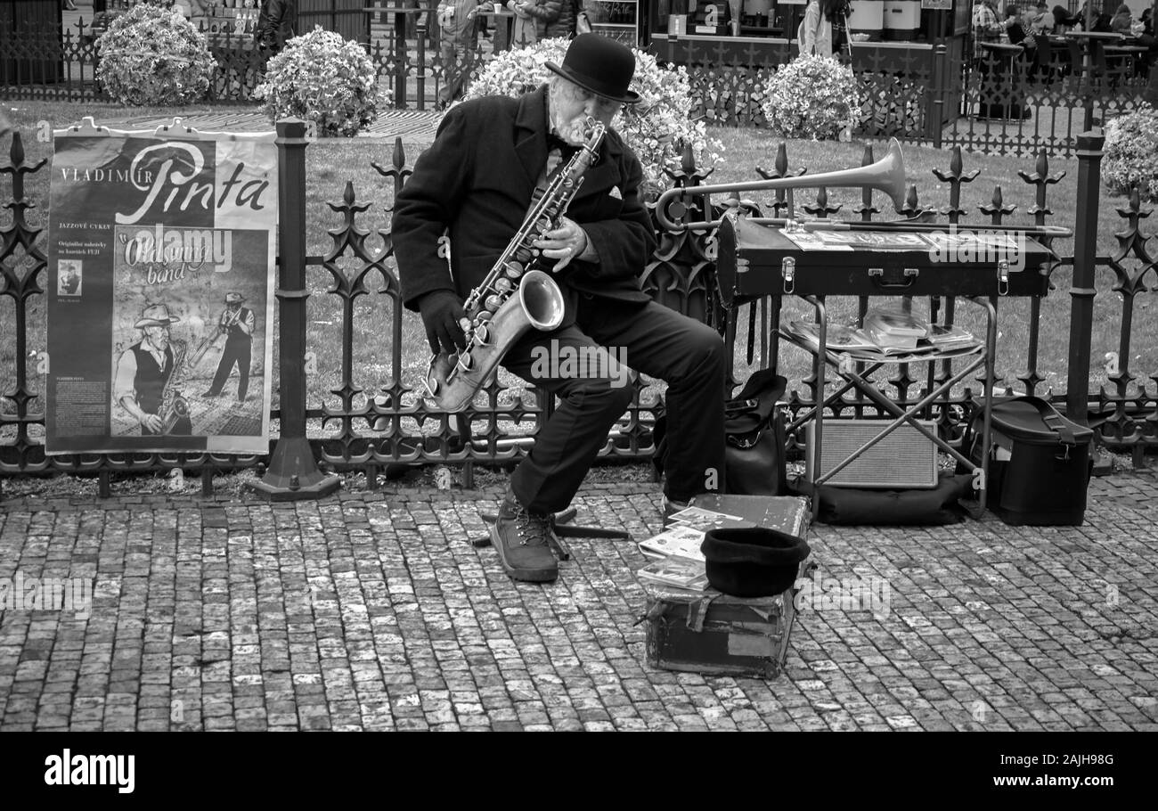 Musicista jazz maschile che suona dal vivo con il suo sassofono per le strade di Praga Foto Stock