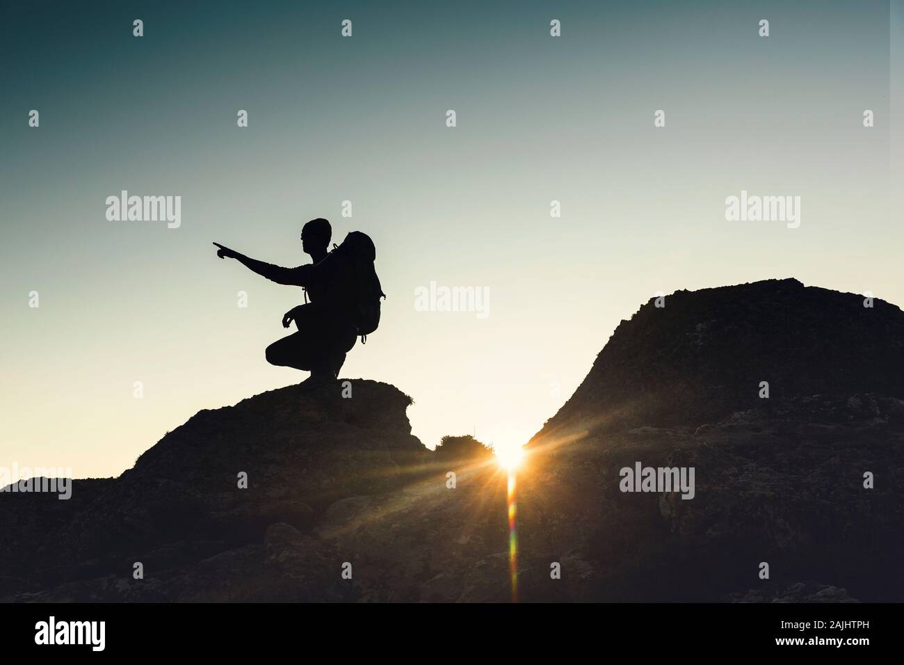 Colpo di un uomo rivolto alla vista delle montagne al tramonto Foto Stock