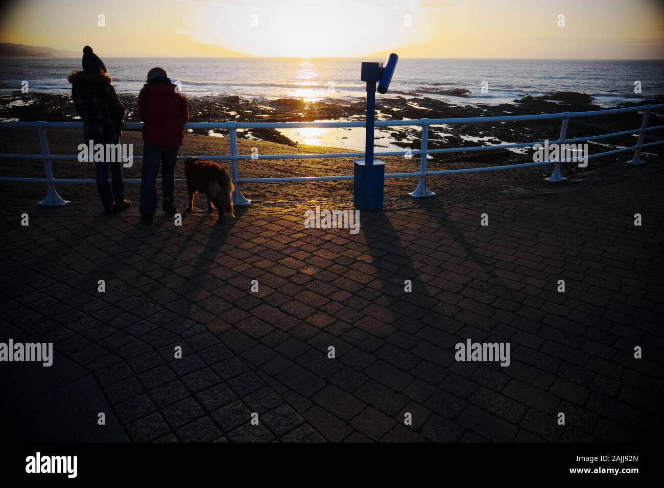 Aberystwyth Wales una coppia con cane Godetevi il tramonto sulla spiaggia Foto Stock