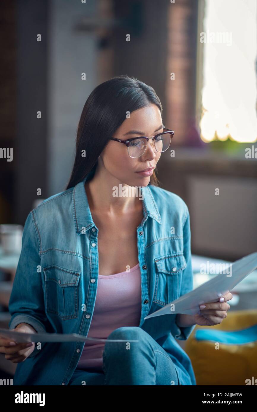 Grave smart giovane donna controllando i documenti Foto Stock