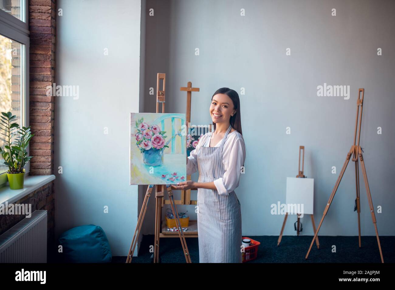 Bella donna di talento che vi mostra una pittura di fiori Foto Stock