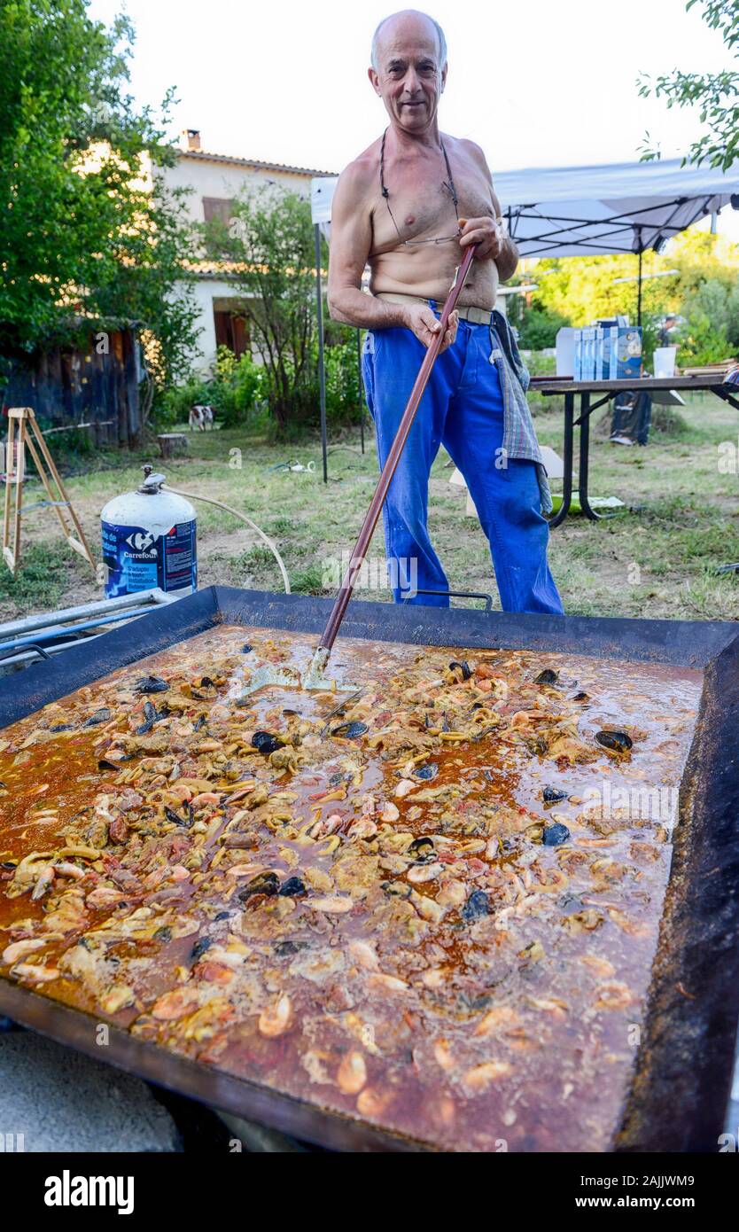 Uomo Paella di cottura all'aperto per 100 + persone Foto Stock