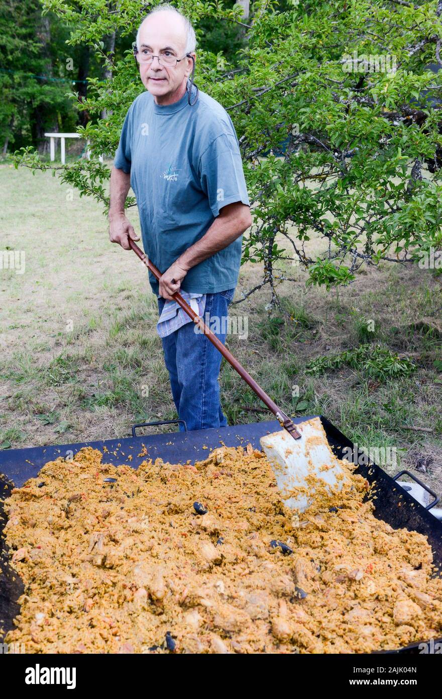 Uomo Paella di cottura all'aperto per 100 + persone Foto Stock