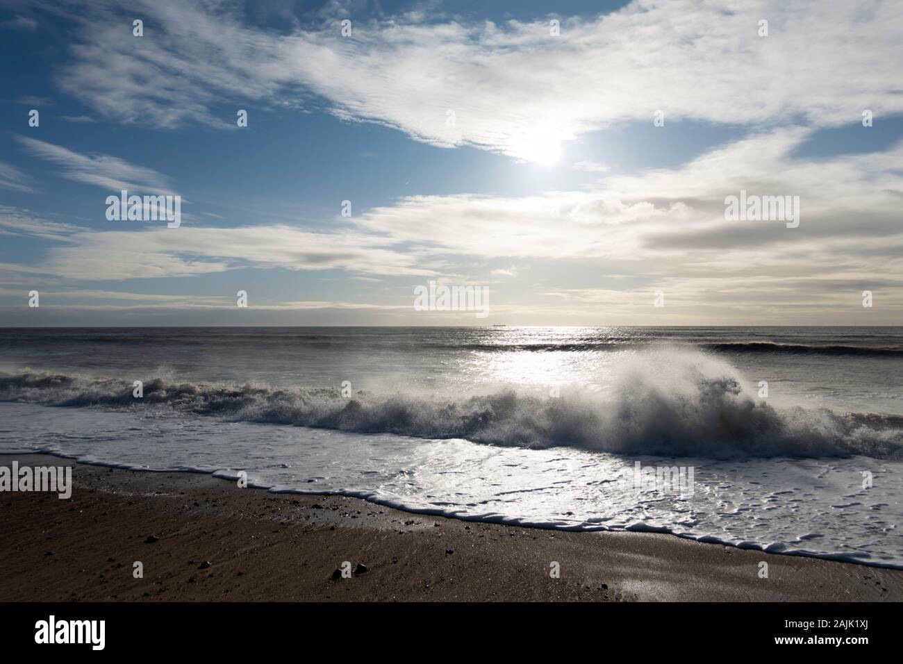 Rottura di onde sulla spiaggia di ciottoli retroilluminati da sole, Shoreham-da-mare; West Sussex; Inghilterra, Regno Unito, Europa Foto Stock