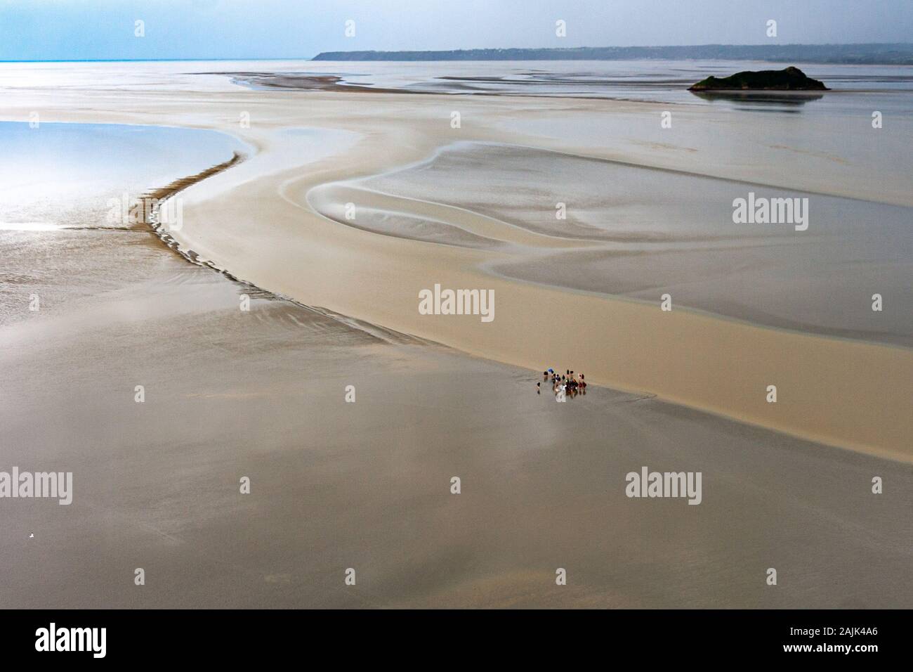 I turisti camminano nelle pianure di fango vicino a Mont Saint-Michel a bassa marea. Normandia, Francia Foto Stock