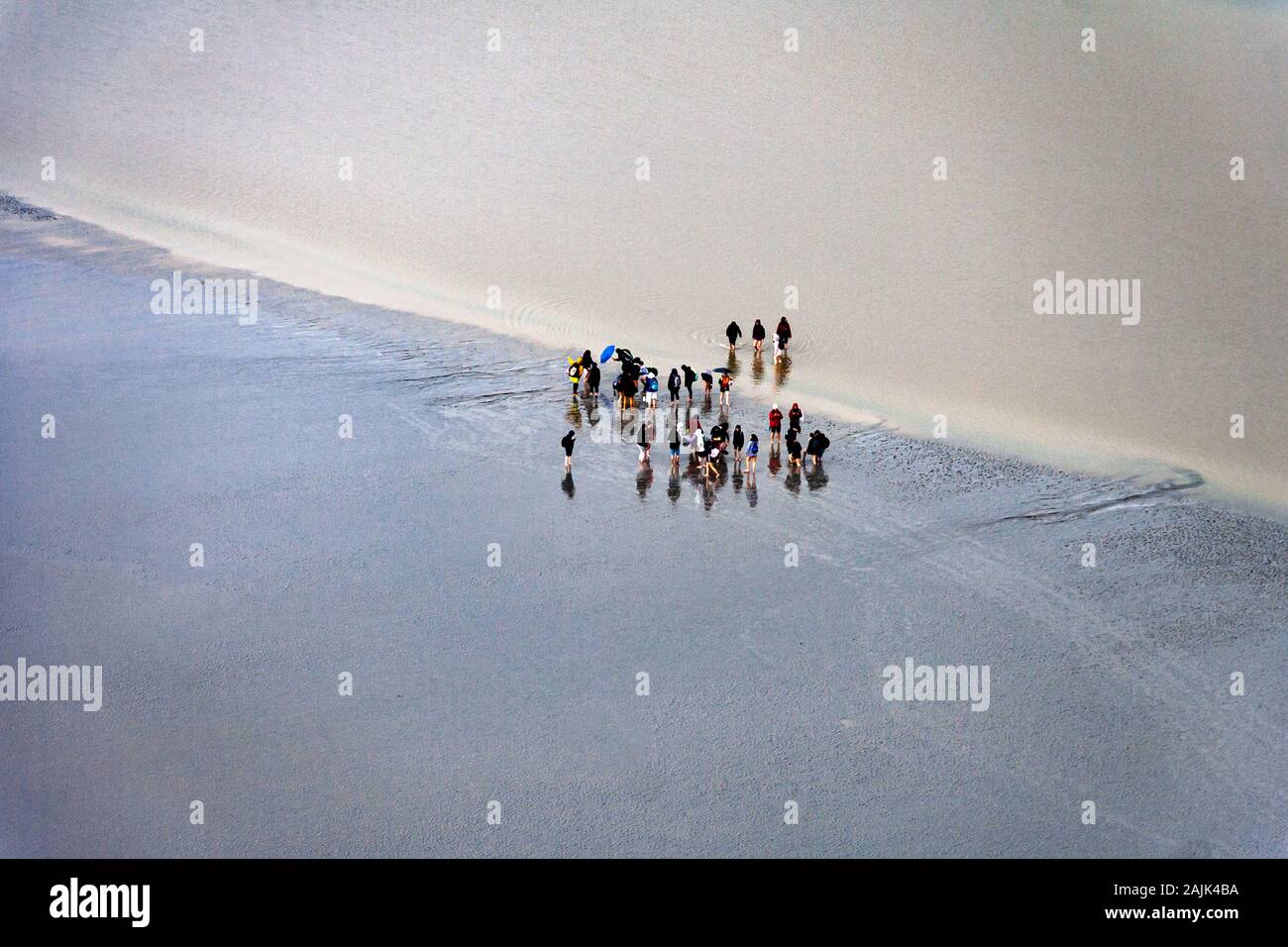 I turisti camminano nelle pianure di fango vicino a Mont Saint-Michel a bassa marea. Mont Saint-Michel, Normandia, Francia Foto Stock