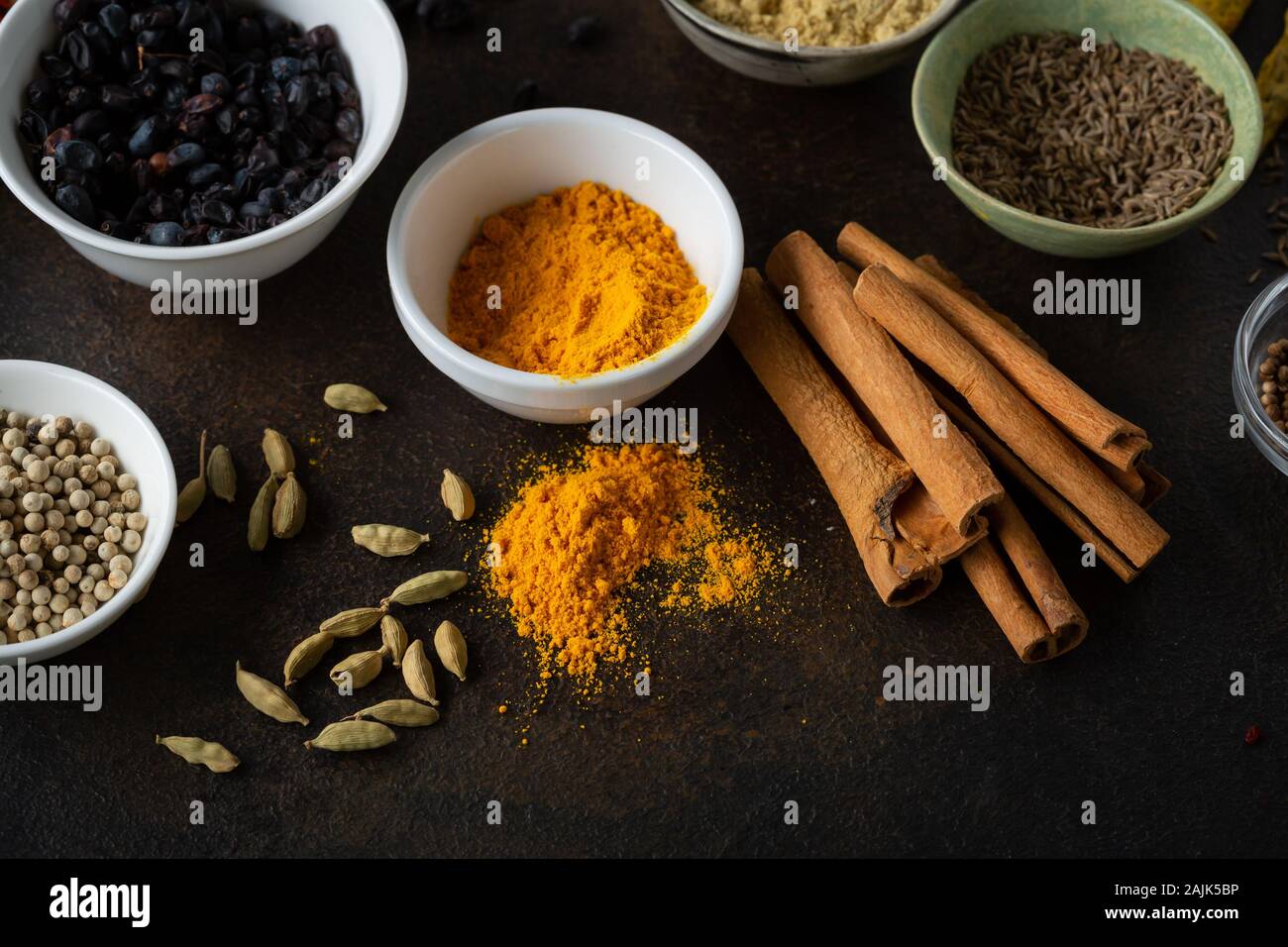 Spezie colorate e condimento in ciotole su sfondo scuro Foto Stock