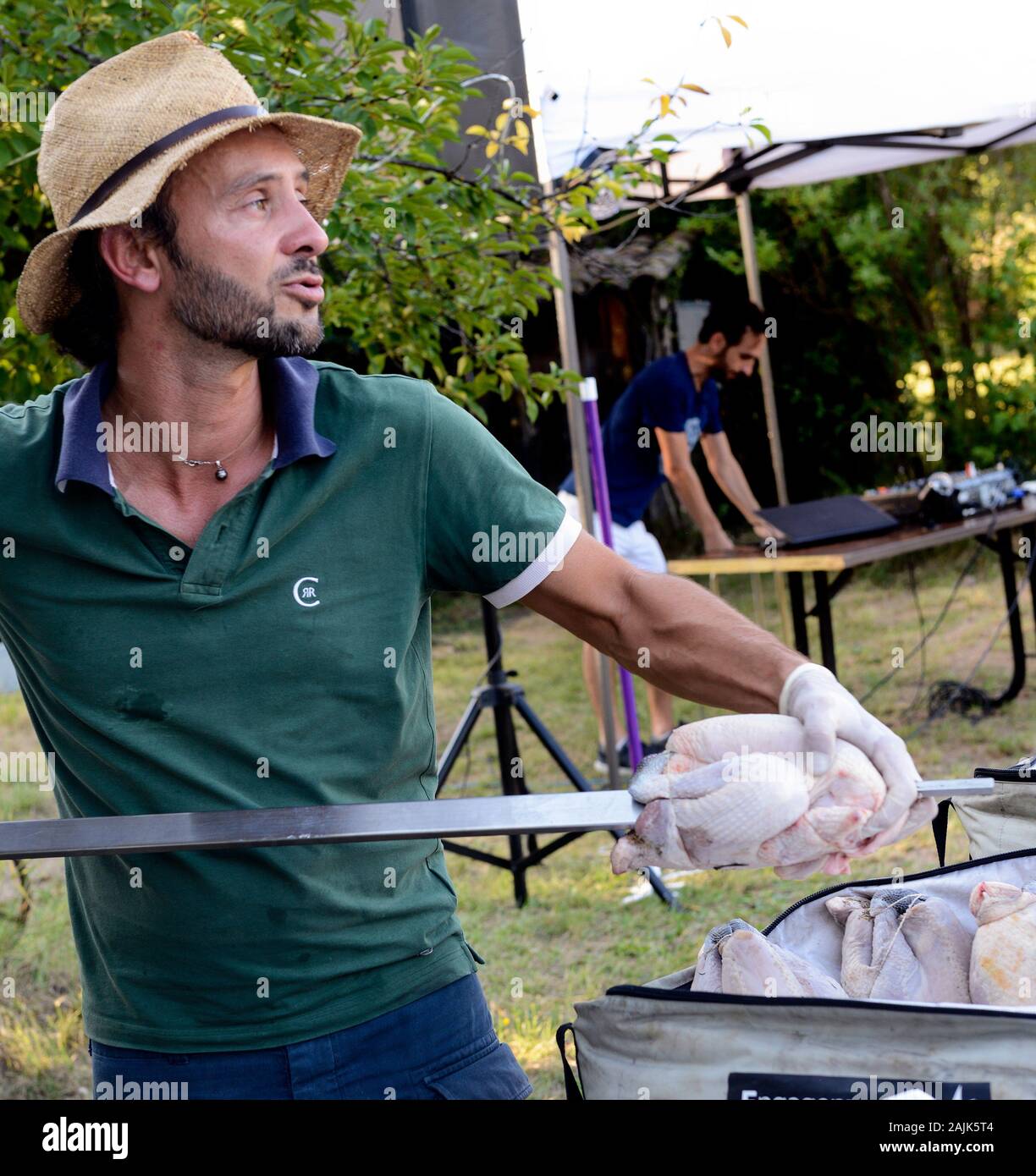 L'uomo la preparazione di pollo arrosto allo spiedo all'aperto Provence Francia Foto Stock