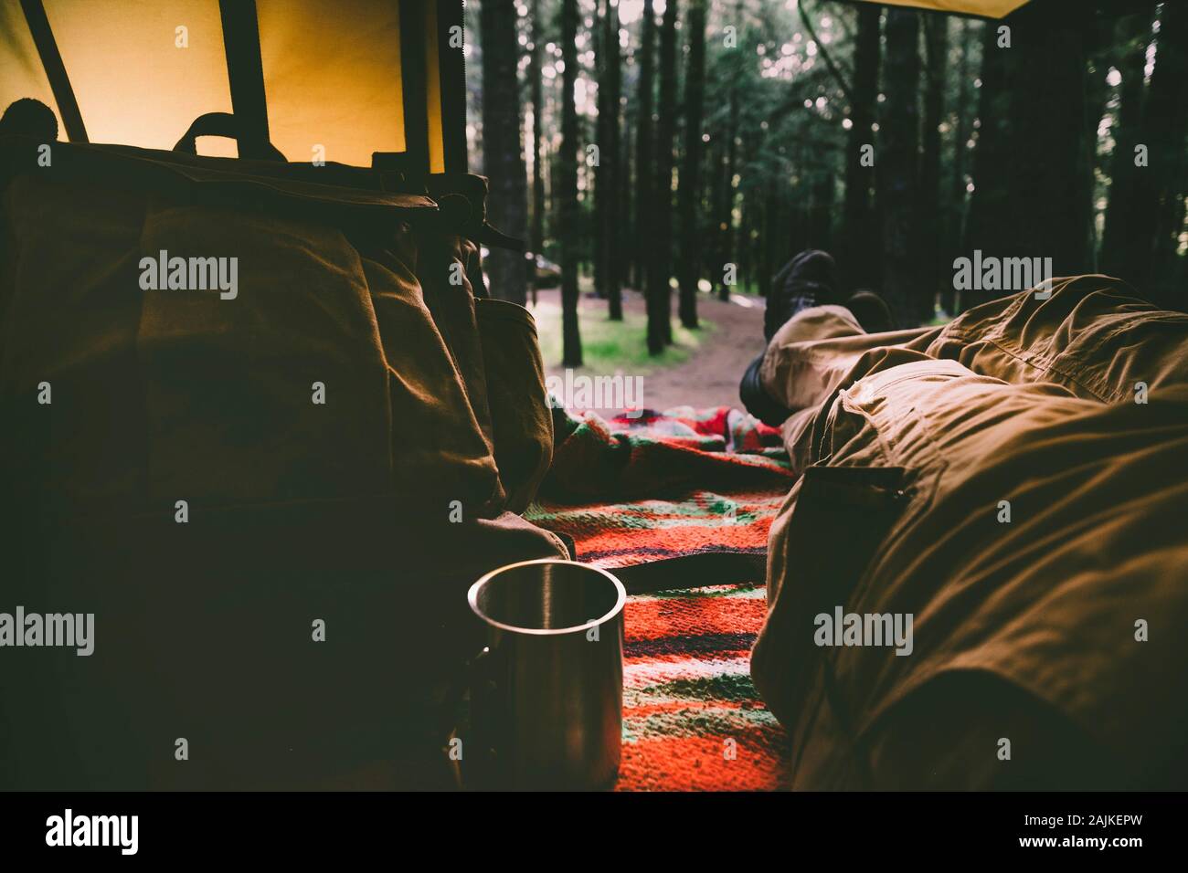 L'uomo gambe punto di vista pov all'interno di una tenda con outdoor bosco selvatico al di fuori - Concetto di wild alternative di vacanza per persone in wanderlus che Foto Stock