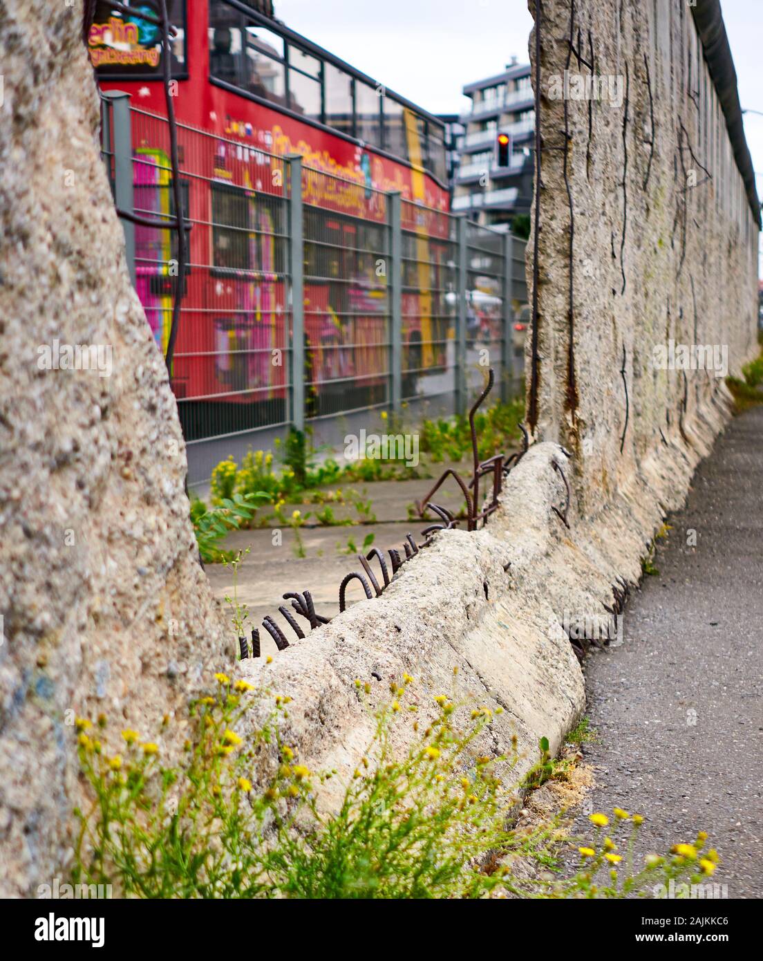 Giustapposizione di un buco nel famigerato muro di Berlino e di un autobus turistico colorato fanno per un pensiero provocante foto. Berlino, Germania Foto Stock