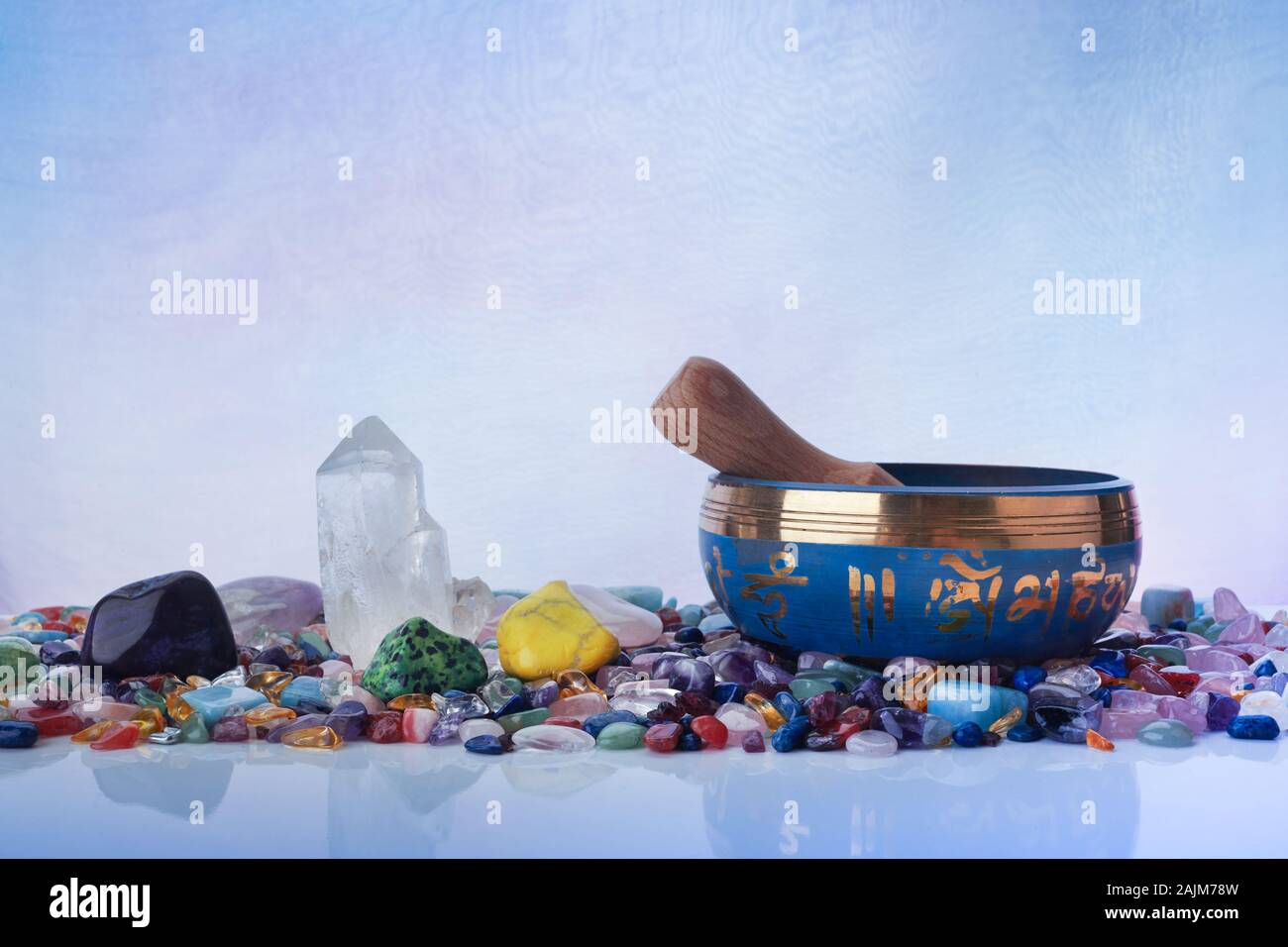 Il Tibetano Singing Bowl e multicolori guarigione pietre contro un sfondo pastello Foto Stock