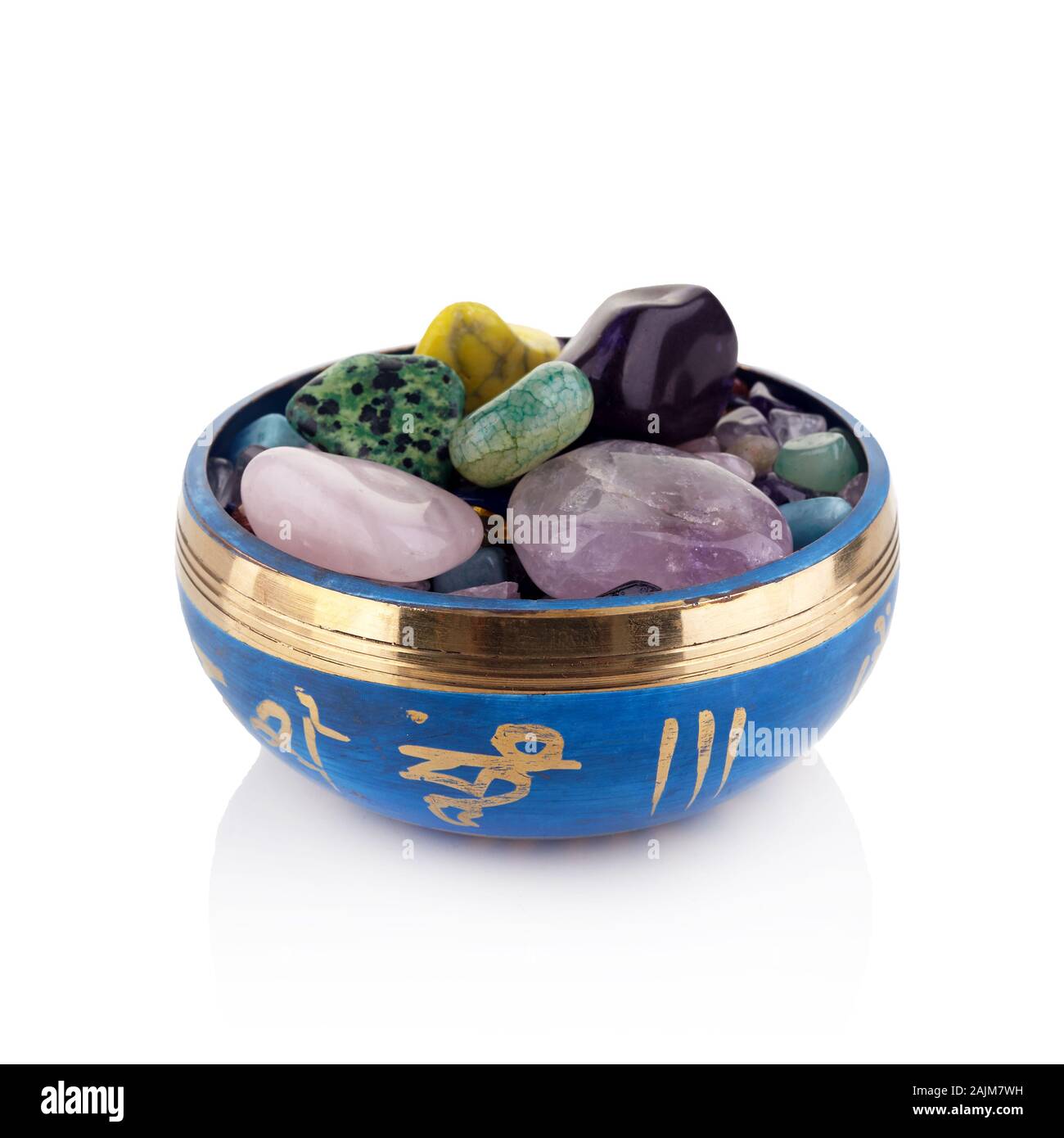 Il Tibetano Singing Bowl e multicolori guarigione pietre contro uno sfondo bianco Foto Stock