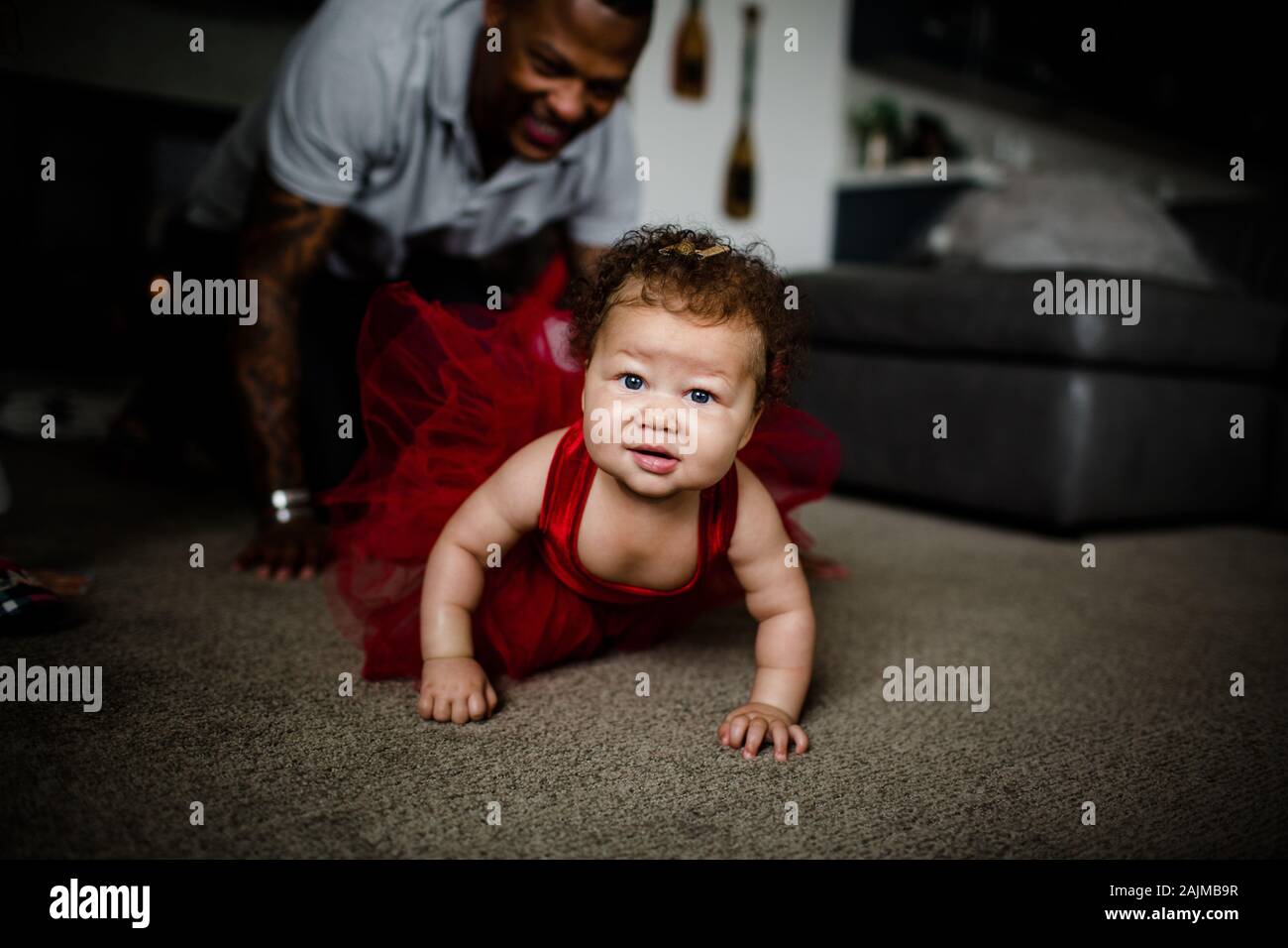 Misto Race Baby strisciando come papà segue dietro Foto Stock