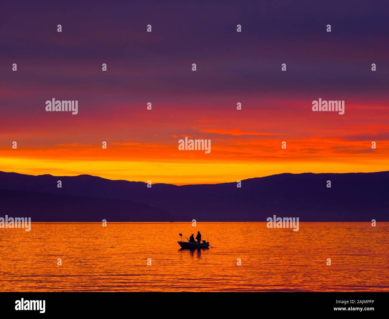 Lonely barca con due pescatori prima di glorioso tramonto scenario del mare Foto Stock