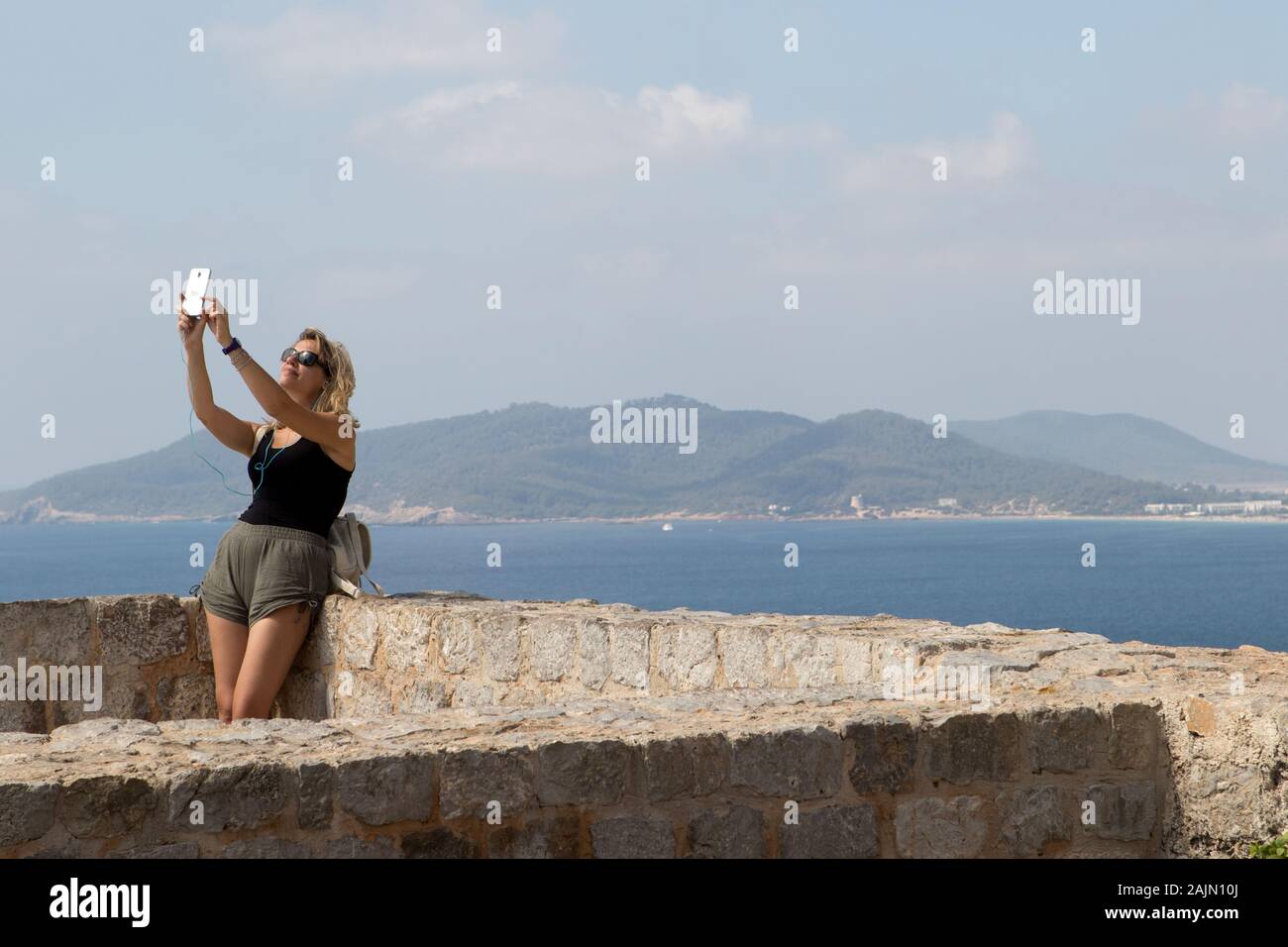 Una turista donna scatta un selfie sulla cima del castello di Eivissa a Eivissa (città di Ibiza) a Ibiza, Isole Baleari, Spagna Foto Stock