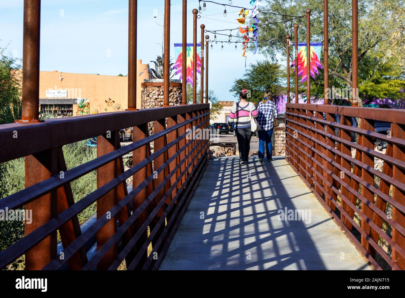 Vista posteriore di due donne passeggiando attraverso la moderna, industriale progettato in metallo passerella pedonale in città artigianale di Tubac, AZ Foto Stock