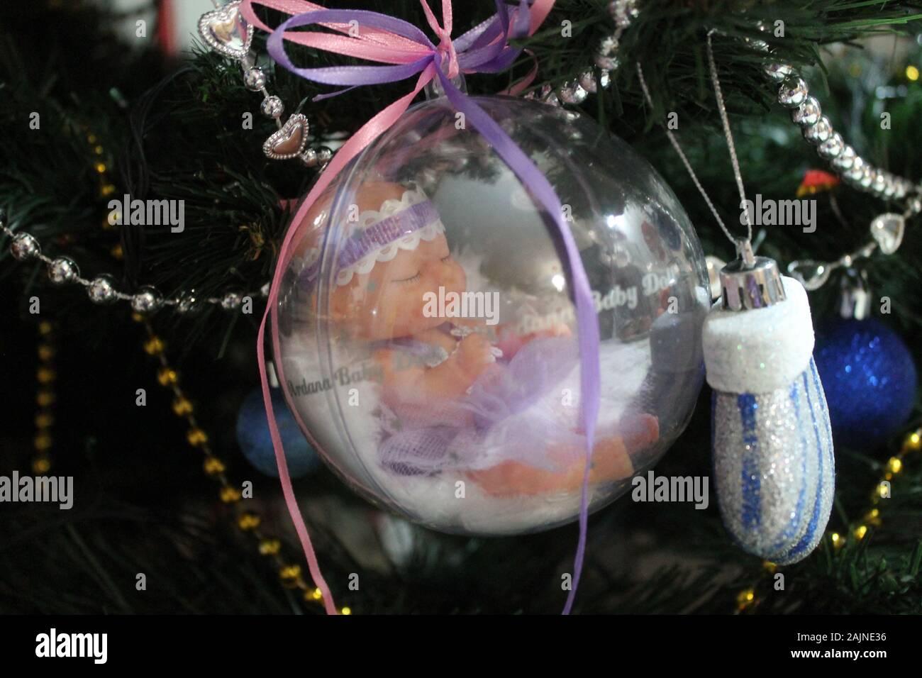 Little baby doll nella sfera di cristallo con nastri colorati per la decorazione sulla vacanza invernale o regalo per ragazze Foto Stock