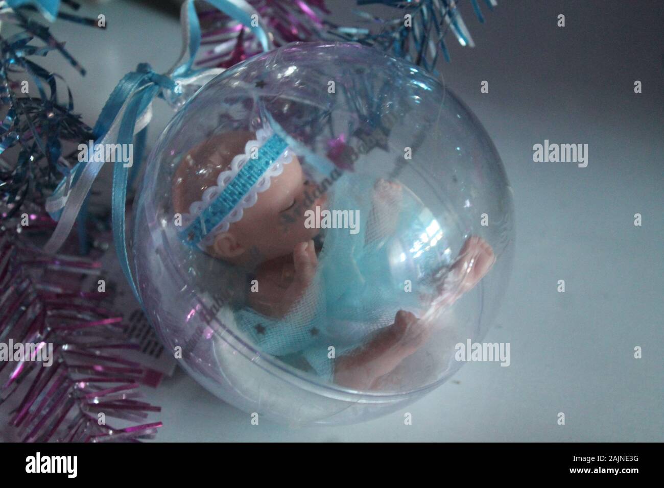 Little baby doll nella sfera di cristallo con nastri colorati per la decorazione sulla vacanza invernale o regalo per ragazze Foto Stock