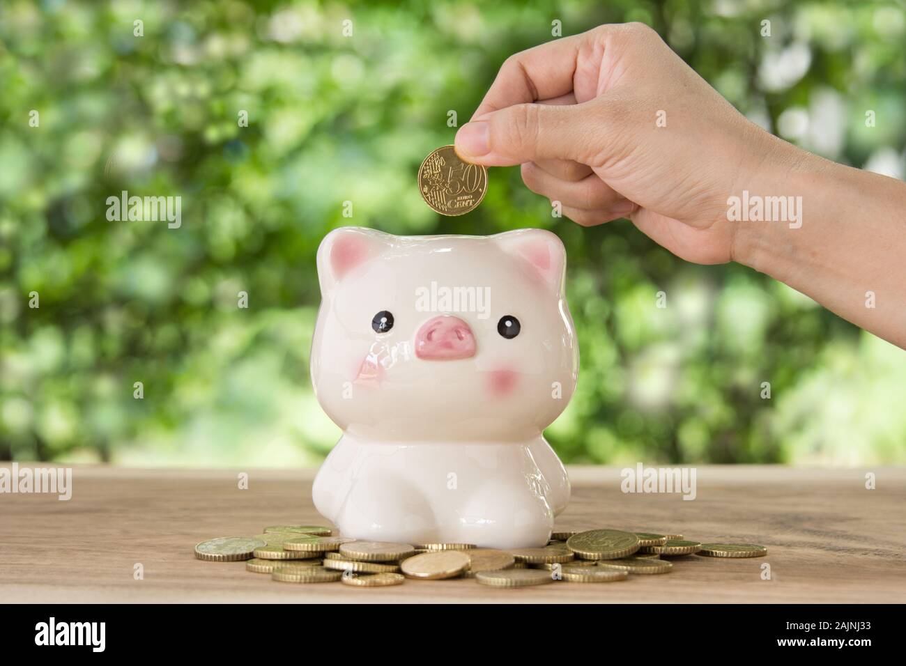 La mano le donne mettendo golden moneta nel salvadanaio. conto concetto,concetto aziendale,finanza concetto. Foto Stock