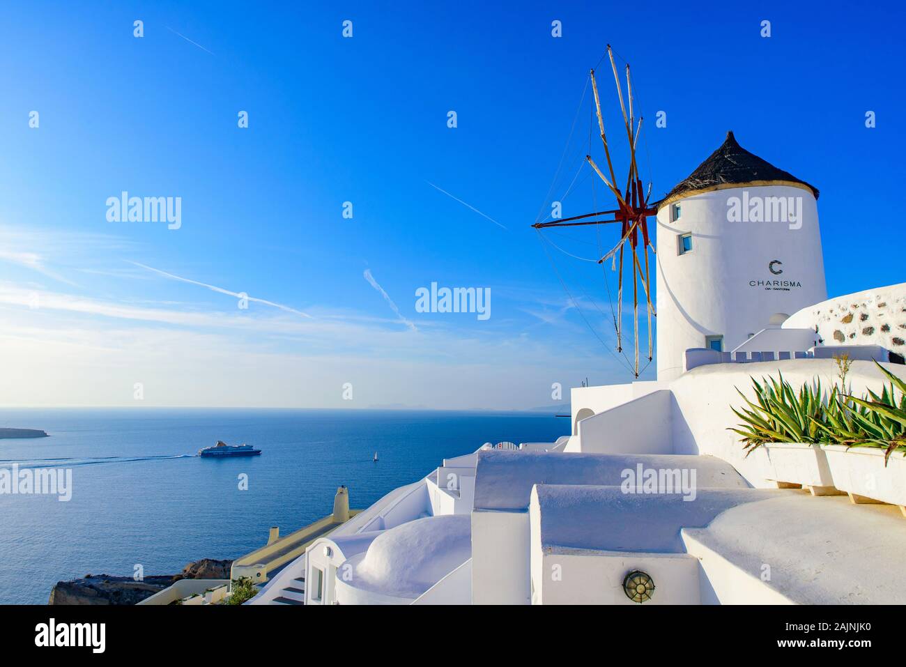 Il mulino a vento e tradizionali edifici bianco rivolto verso il Mare Egeo in Oia - Santorini, Grecia Foto Stock