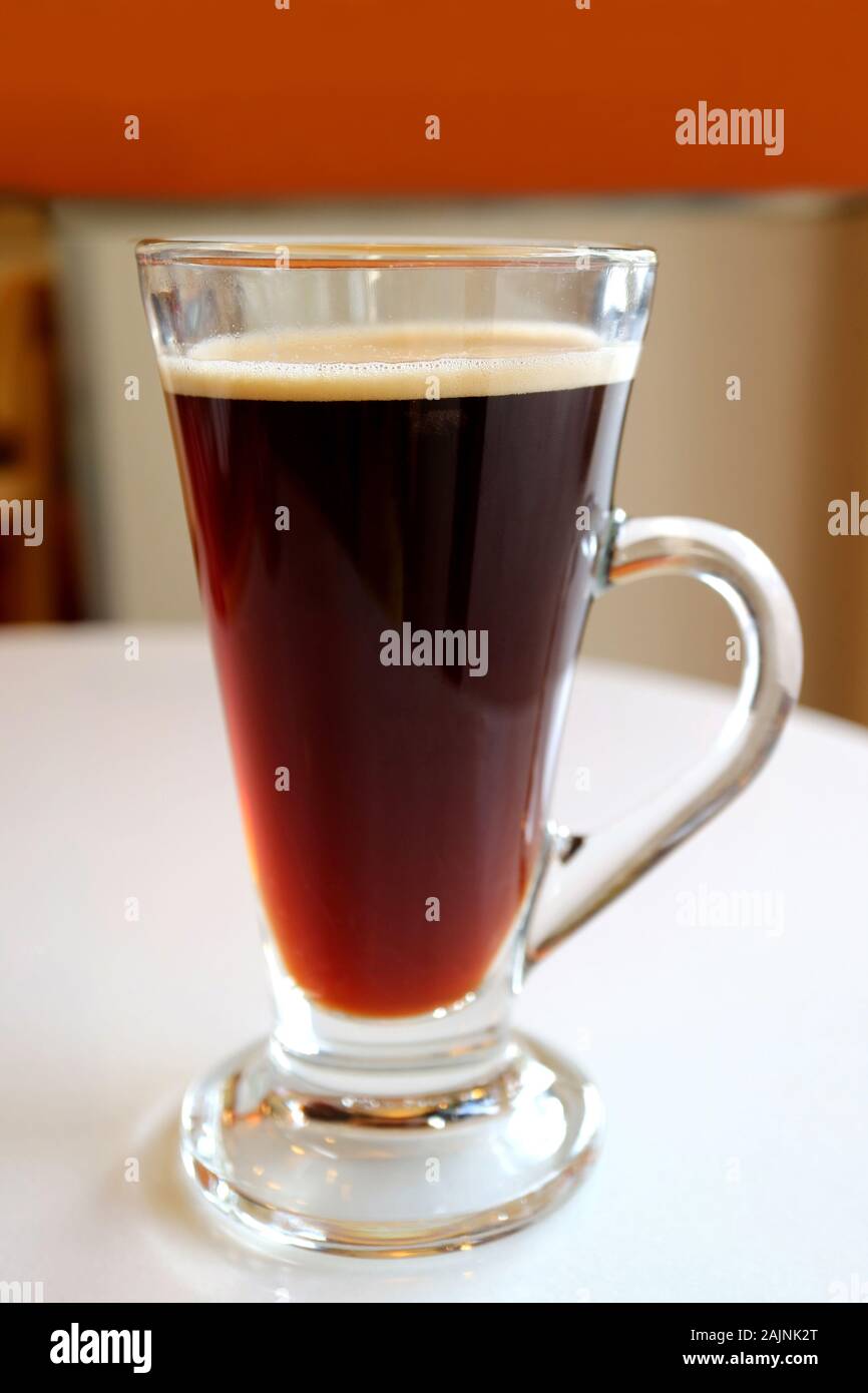Hot caffè nero in un vetro trasparente servito sul tavolo bianco Foto Stock