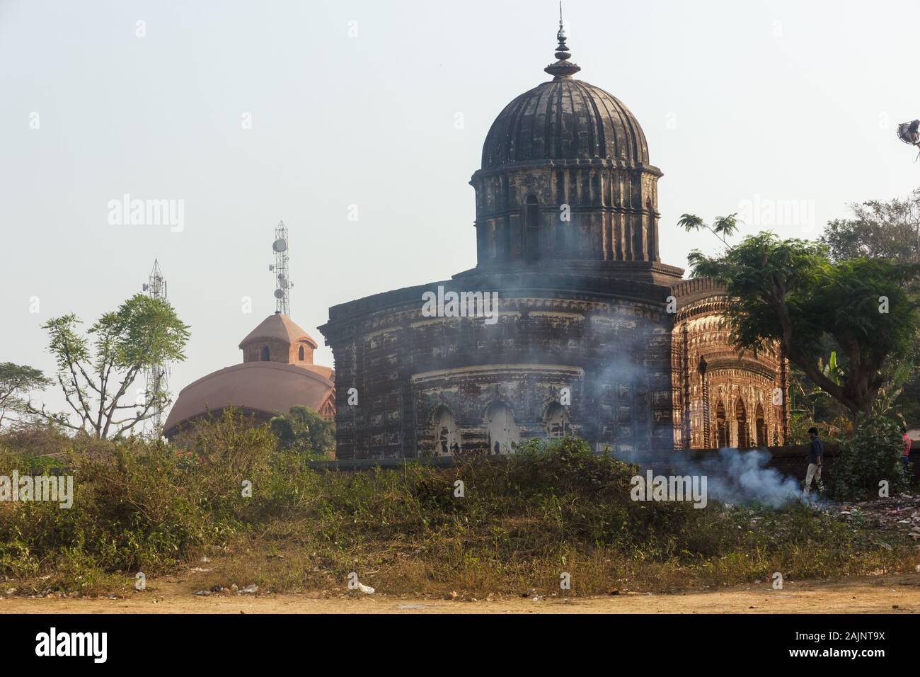 Il bellissimo, antico, tempio indù di Radha Shyam visto dalla strada. Il fumo sale dalla plastica che brucia all'esterno delle sue pareti. Foto Stock