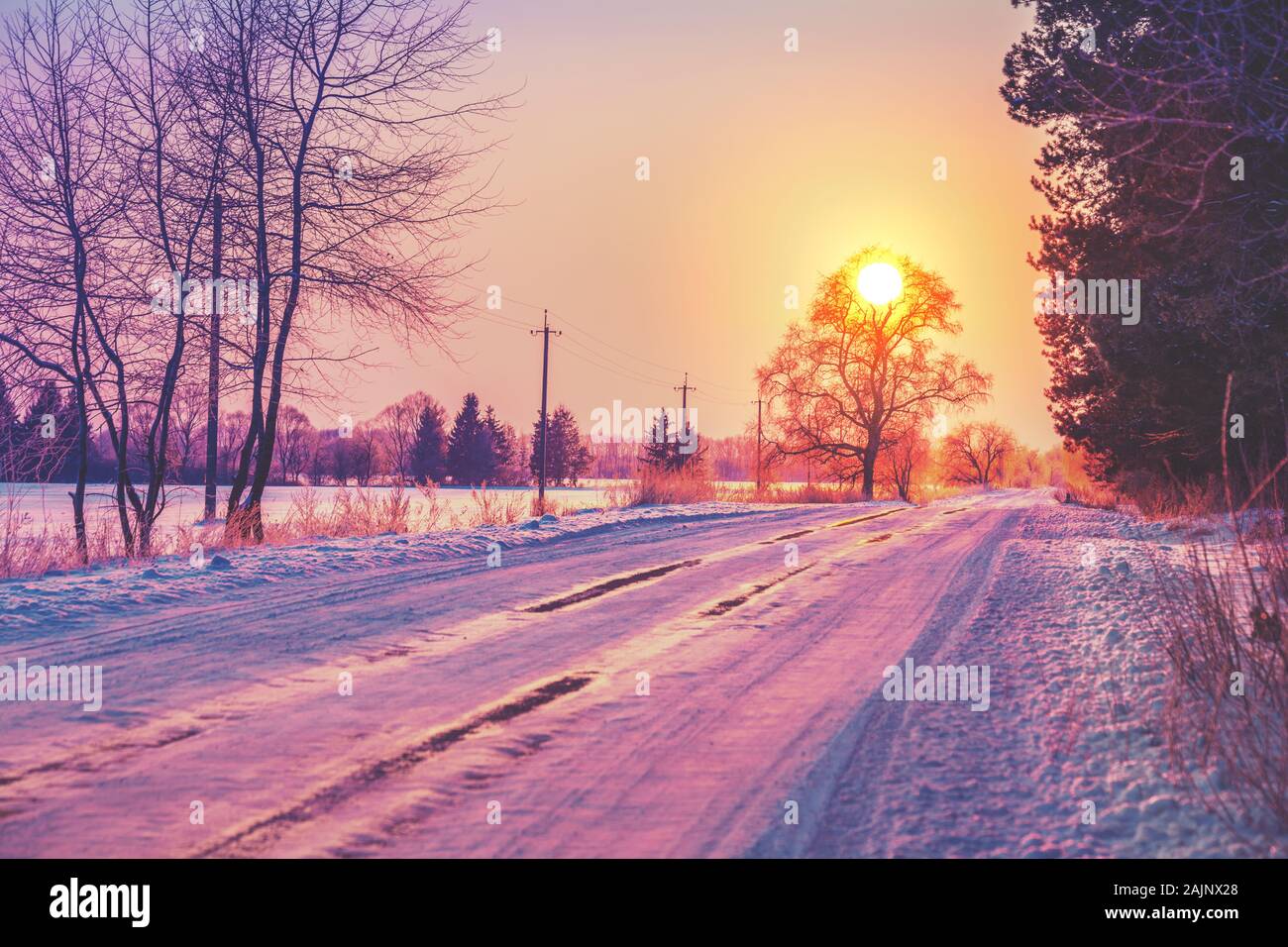 Rurali paesaggio invernale a sunrise. Paese strada coperta di neve Foto Stock