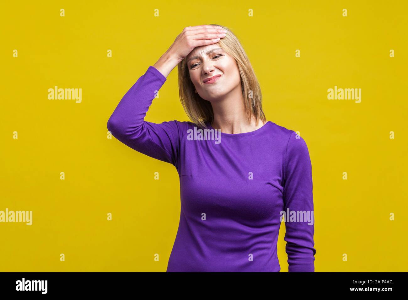 Facepalm, cattiva memoria concetto. Ritratto di sconvolgere smemorati donna in elegante abito viola in piedi con la mano sulla testa, disperatamente cercando di ricordare. Foto Stock