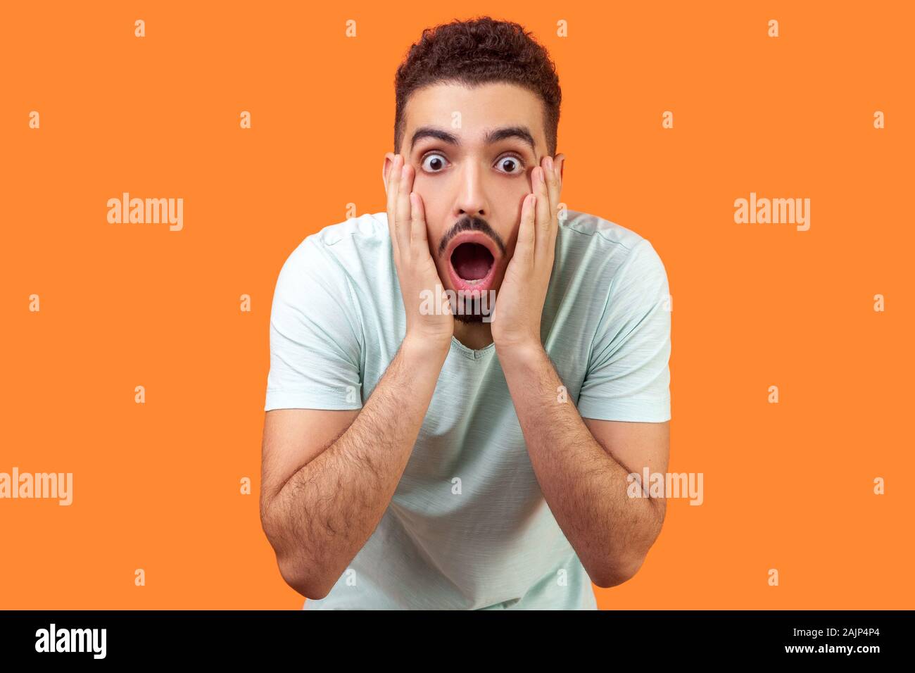 Incredibile sconvolgente notizia! Ritratto di storditi brunette uomo con la barba in casuale t-shirt bianca con faccia di contenimento e di mantenere la bocca aperta in segno di stupore. Foto Stock