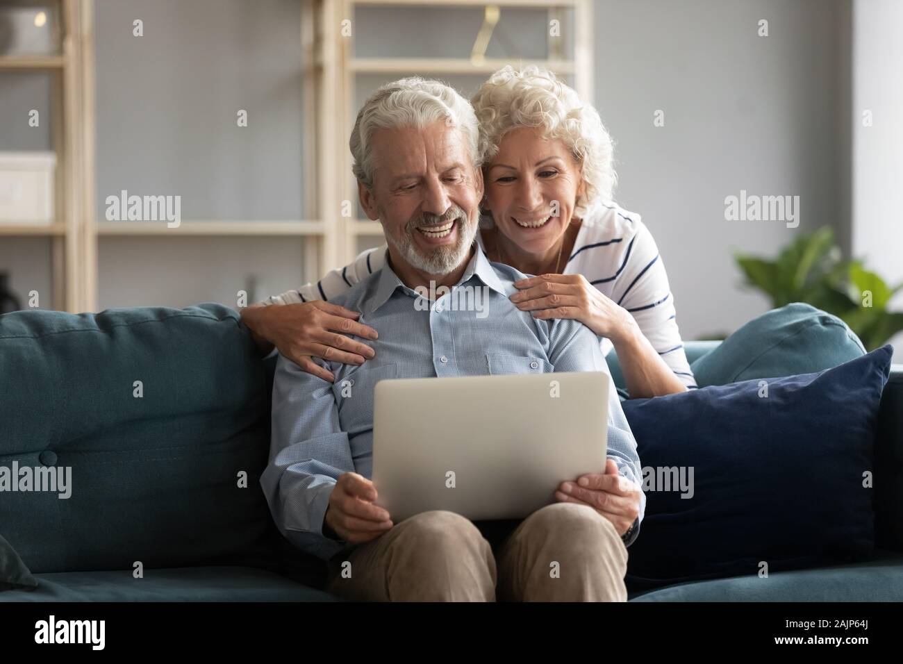 Anziani coniugi avente videocall chiacchierando con cresciuti i bambini online Foto Stock