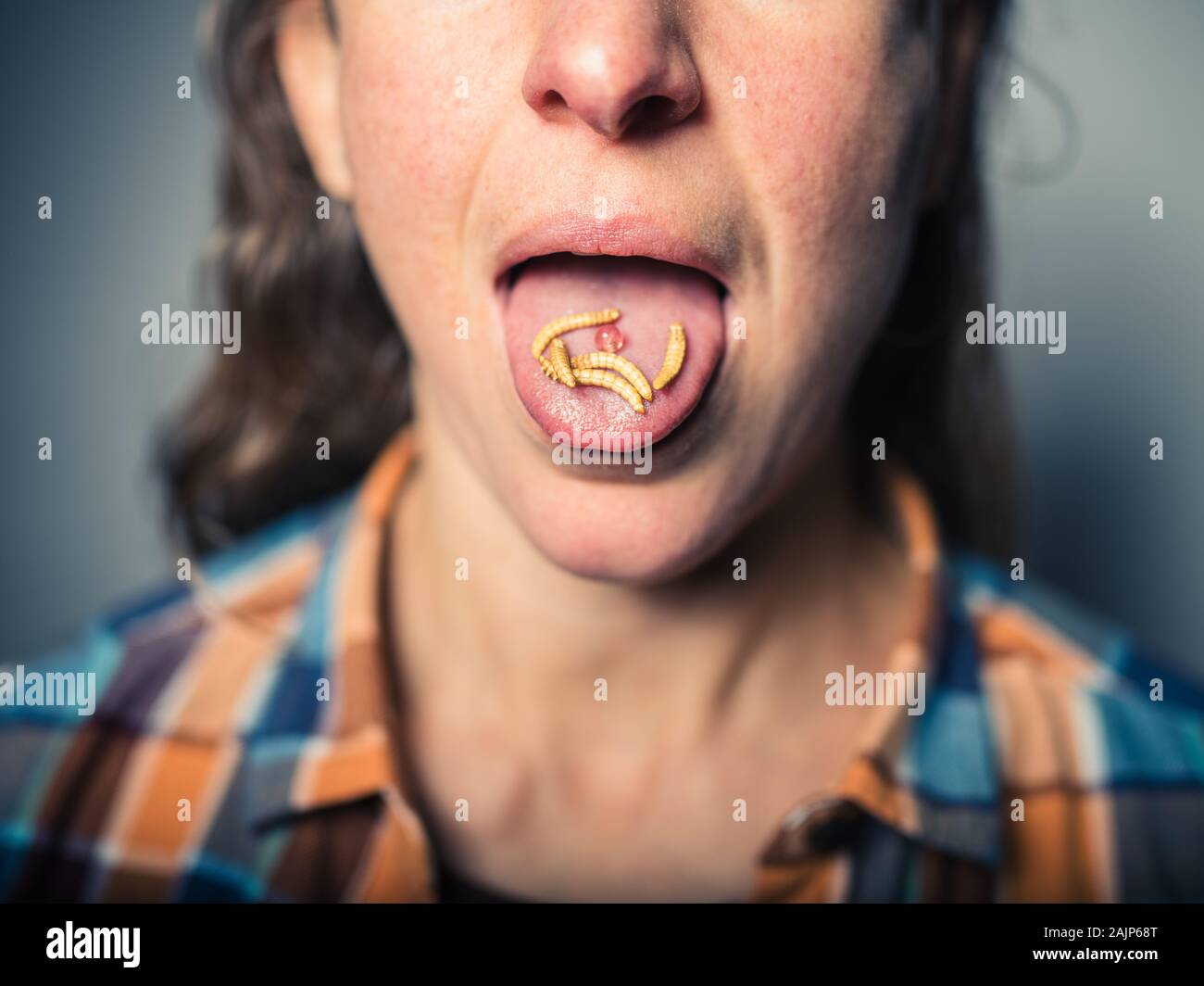 Una giovane donna con vermi commestibili sulla sua lingua Foto Stock