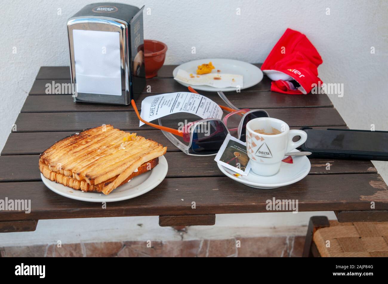 Turisti in bicicletta a riposo in corrispondenza di una piccola caffetteria in un pittoresco blu e bianco linea case una strada in un piccolo borgo nel Comune di Obidos, Portogallo Foto Stock