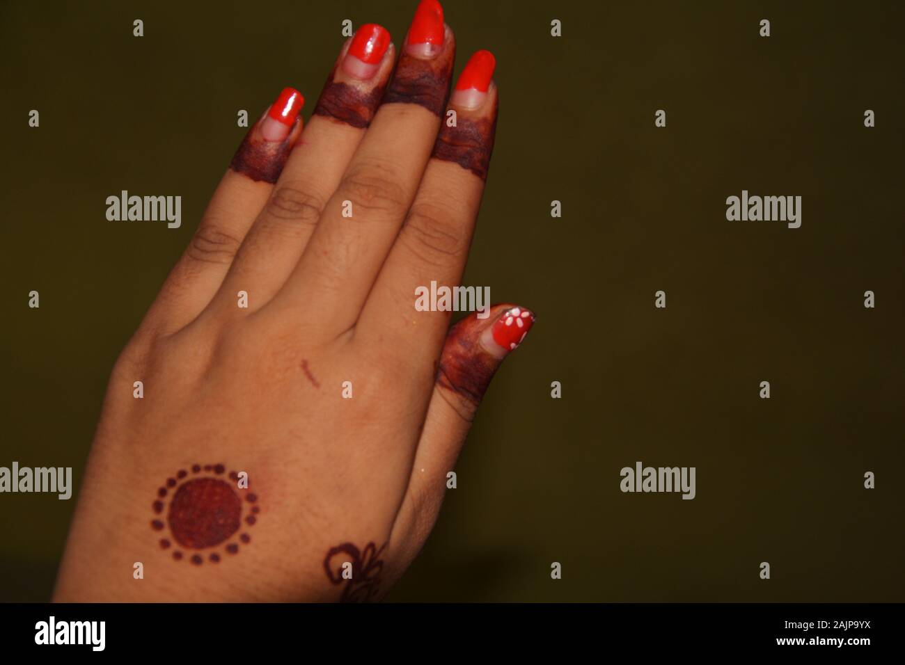 Close up della mano sinistra della ragazza con il rosso smalto per unghie e mehndi in disegni di dita e medio della mano, messa a fuoco selettiva Foto Stock
