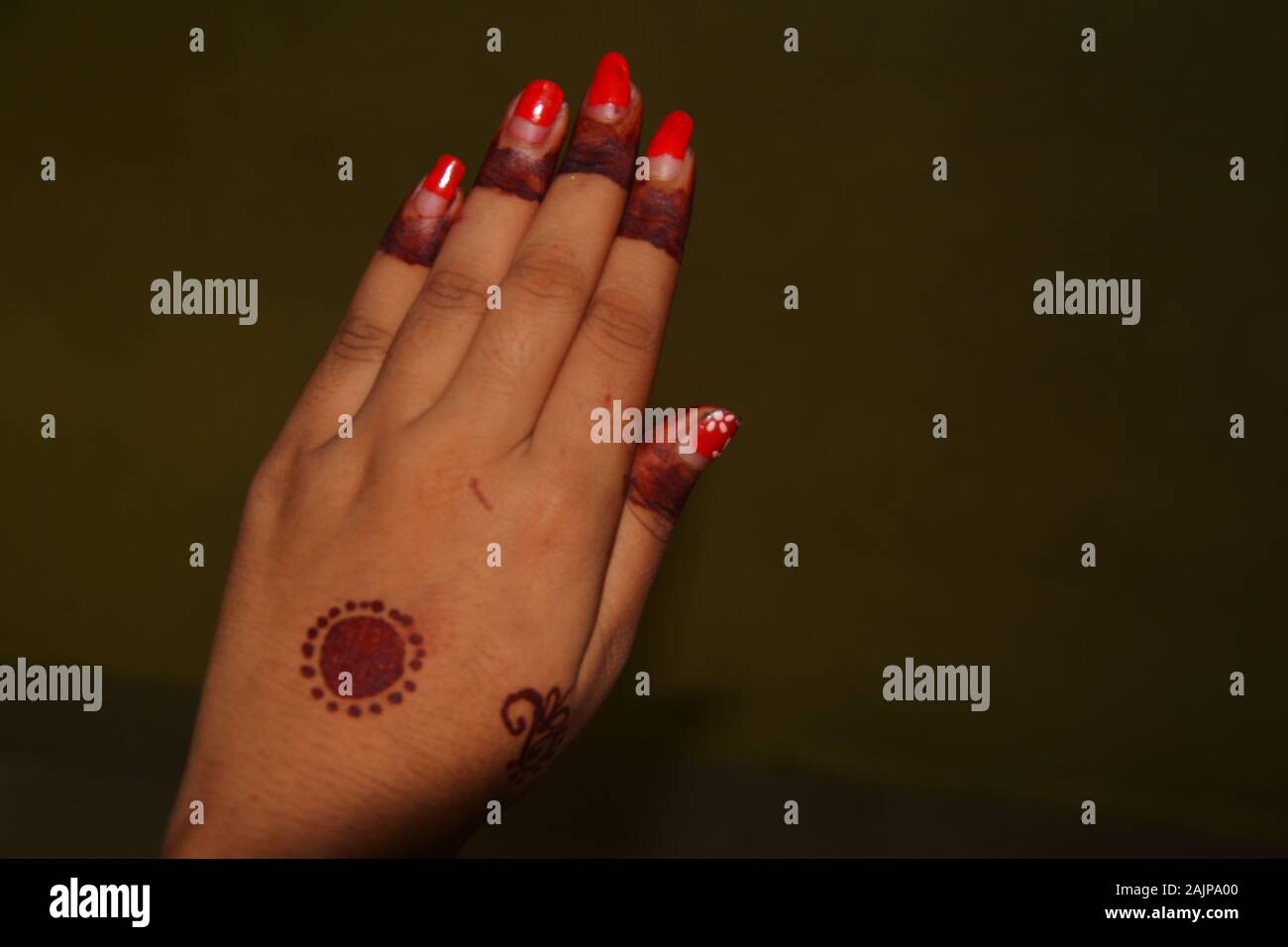 Close up della mano sinistra della ragazza con il rosso smalto per unghie e mehndi in disegni di dita e medio della mano, messa a fuoco selettiva Foto Stock