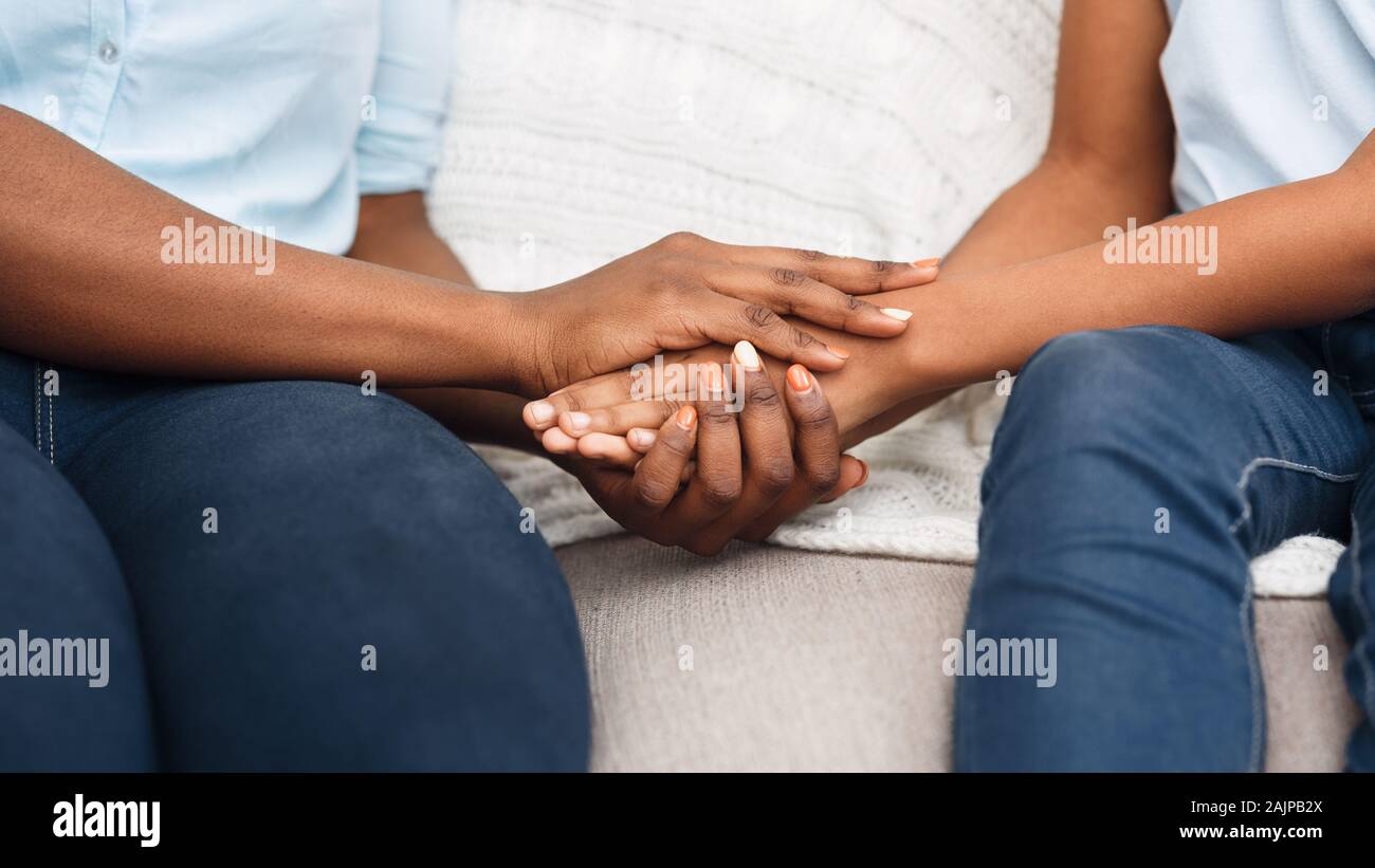 Close up Nero donna e bambino seduto sul lettino tenendo le mani dicendo Siamo spiacenti, scusarsi Foto Stock