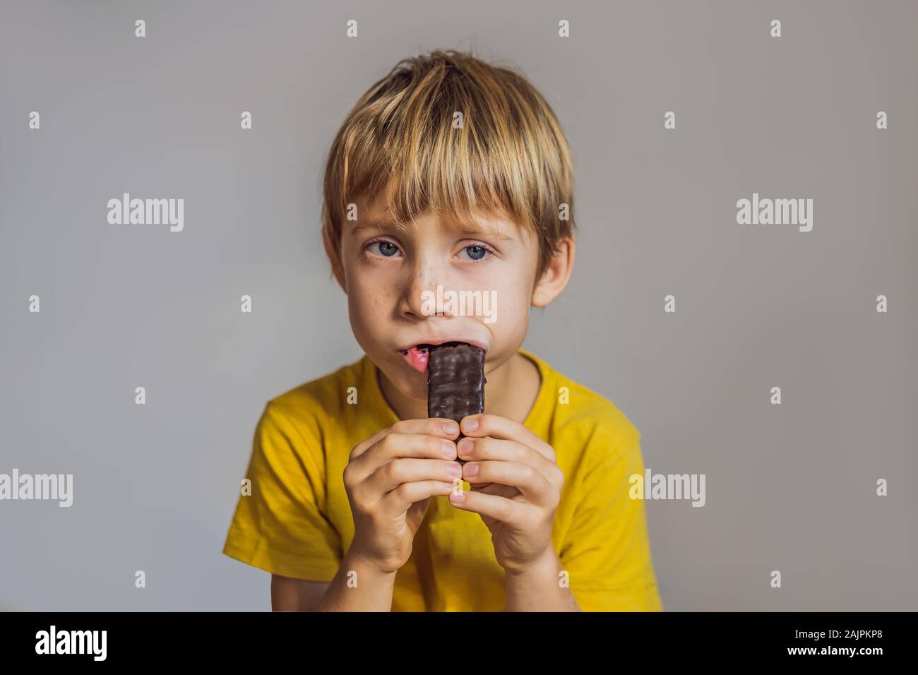Chiusura del giovane ragazzo di mangiare una barretta di cioccolato Foto Stock