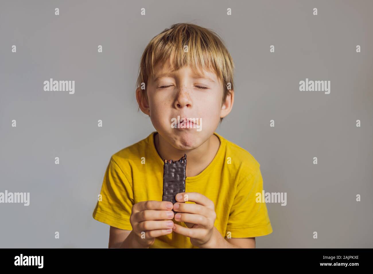 Chiusura del giovane ragazzo di mangiare una barretta di cioccolato Foto Stock