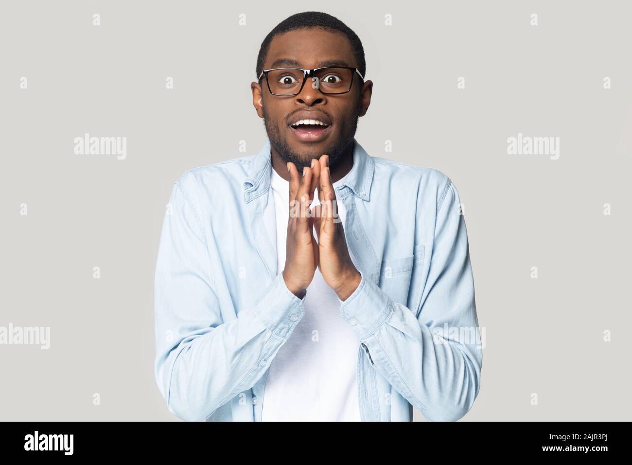Ragazzo africano in attesa di un miracolo isolato su sfondo grigio Foto Stock