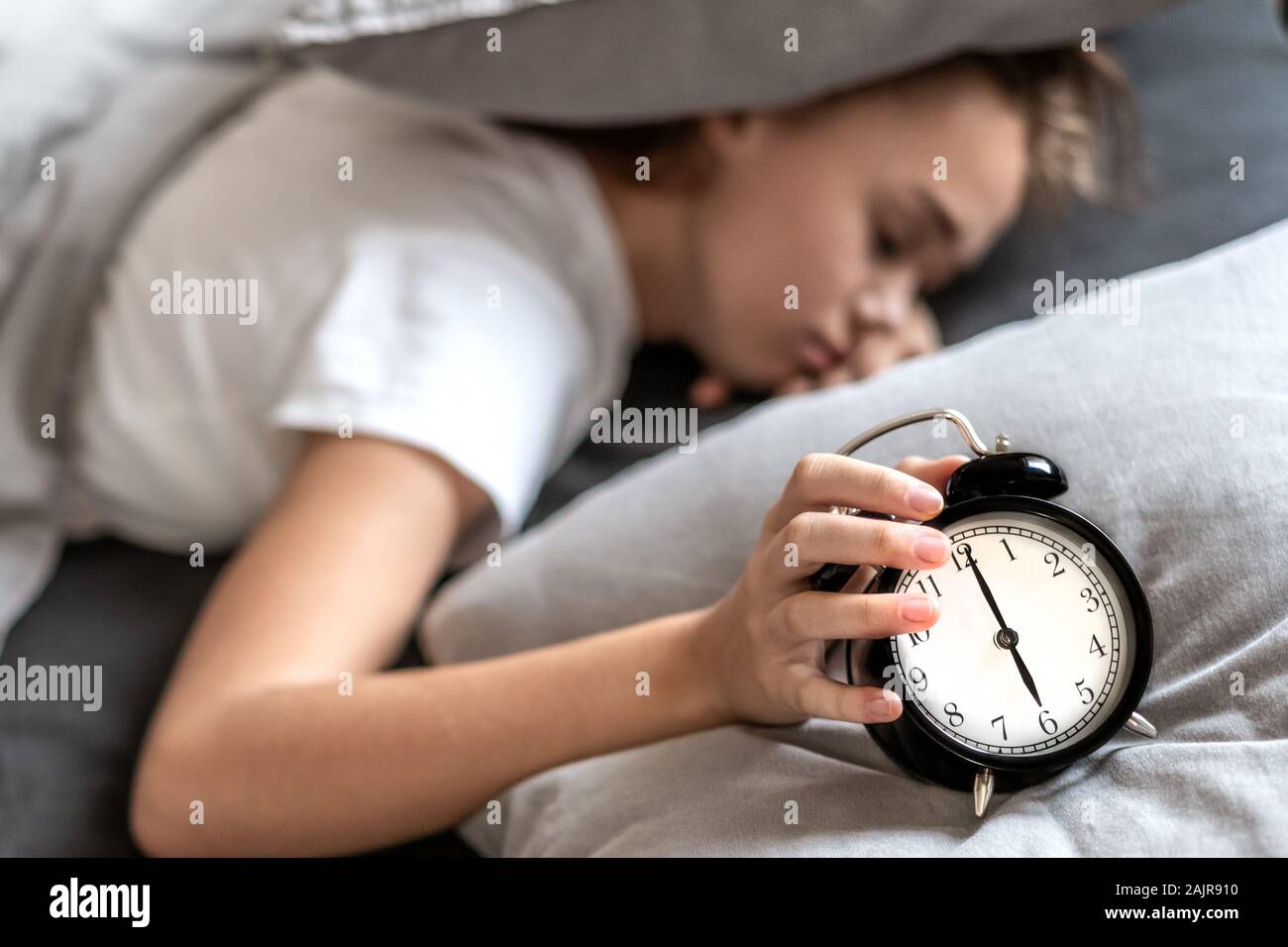 Donna con insonnia che giace nel letto con la sua testa sotto il cuscino cercando di dormire. Insonnia e problemi di sonno. Rilassarsi e dormire concetto. Si sente assonnato e stanco. Foto Stock