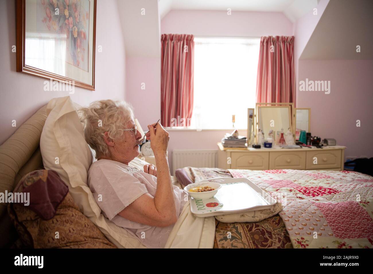 83 enne donna anziana, mangiare il suo pranzo da sola nel letto, England, Regno Unito Foto Stock