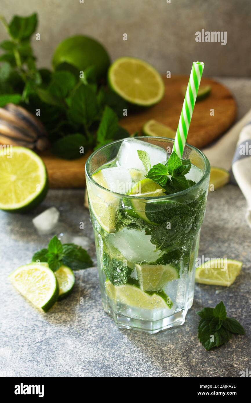 Freschi cocktail mojito con calce, ghiaccio e menta in un bicchiere su una pietra grigia sullo sfondo. Estate freddo drink e cocktail. Foto Stock