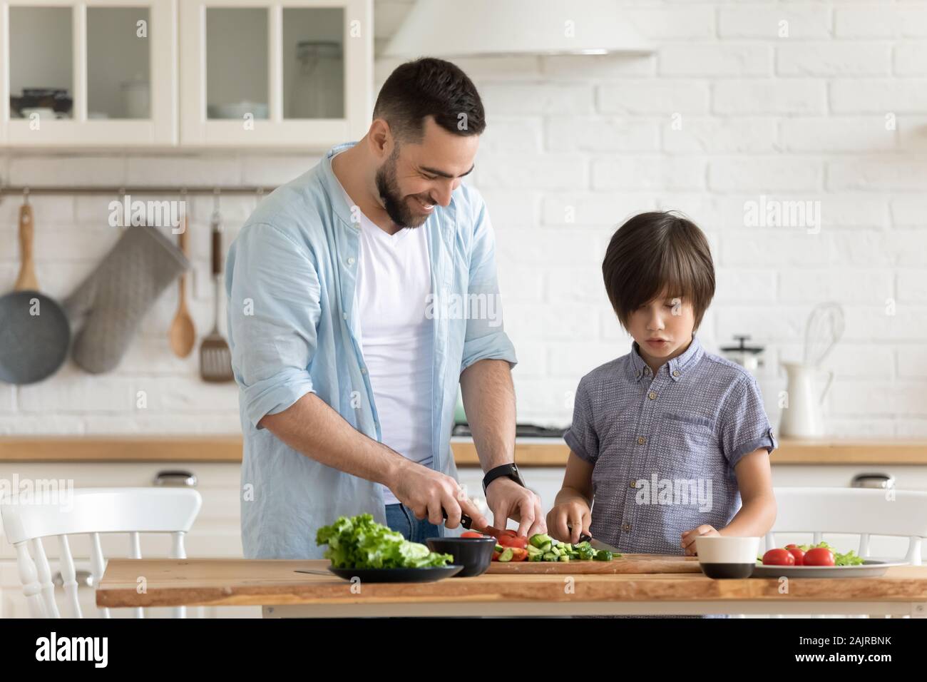 Il Daddy e piccolo figlio di preparare insalata di verdure insieme in cucina Foto Stock