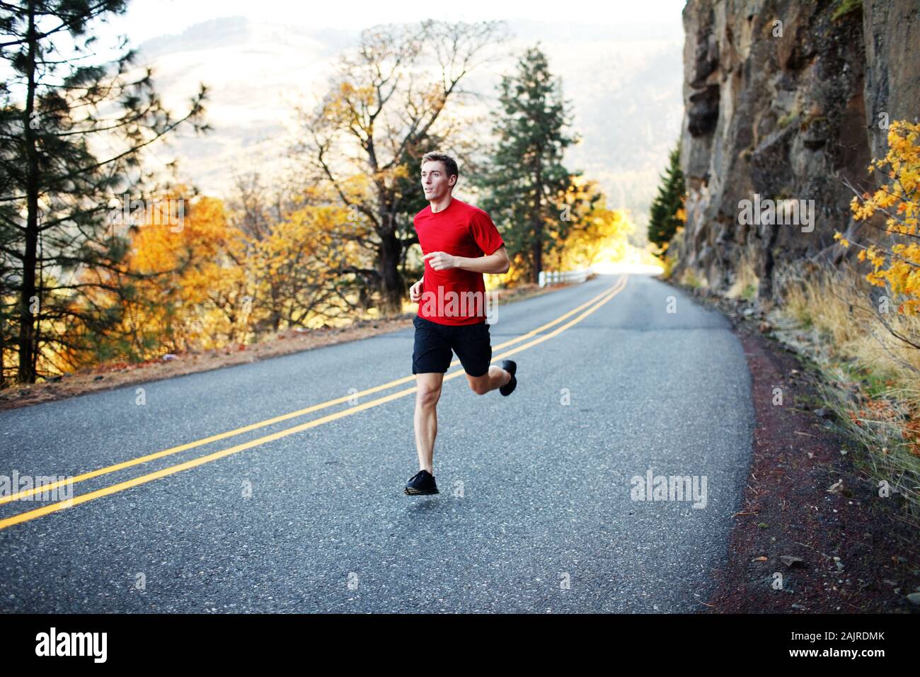 Runner maschile nella sua metà degli anni 20 che corre lungo la strada panoramica a Rowena Foto Stock