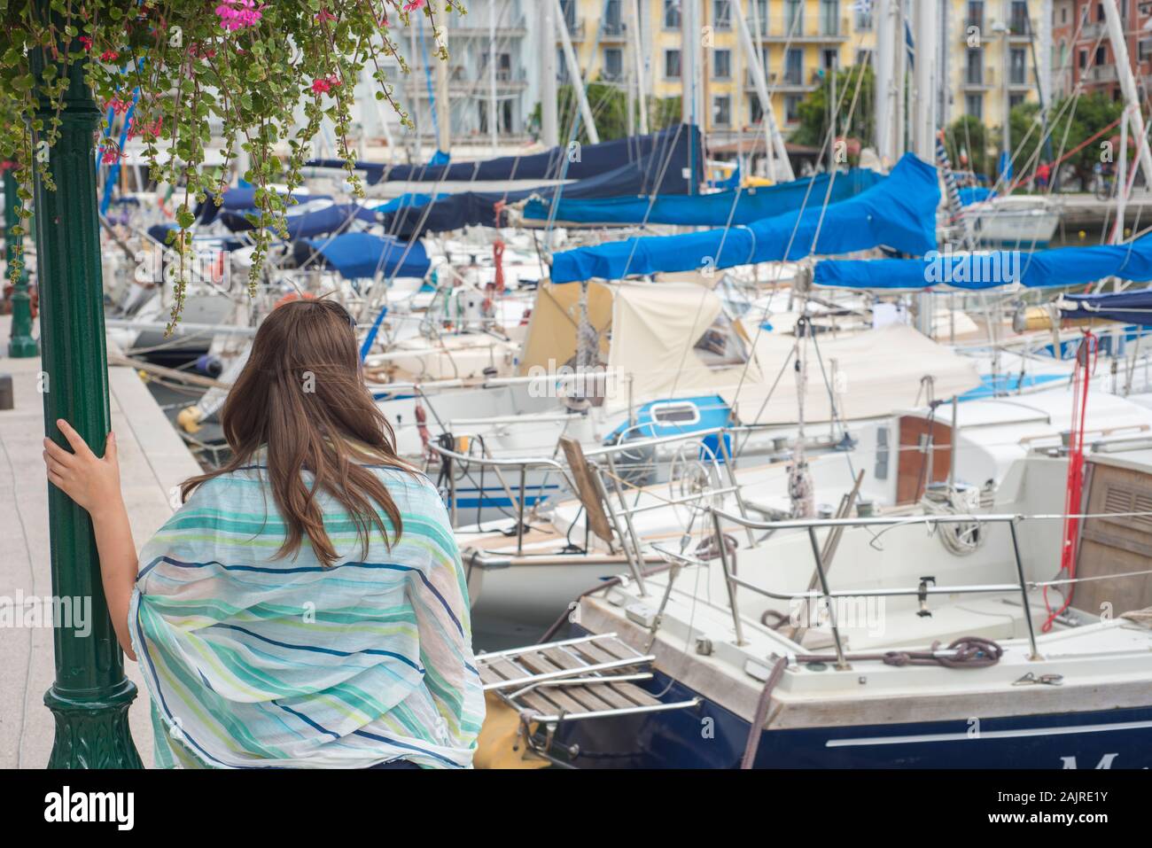 Donna turistica in appoggio in una famosa destinazione turistica con barche nel porto di mare poggiando su strada la luce sotto il bel fiore sommer arangement Foto Stock