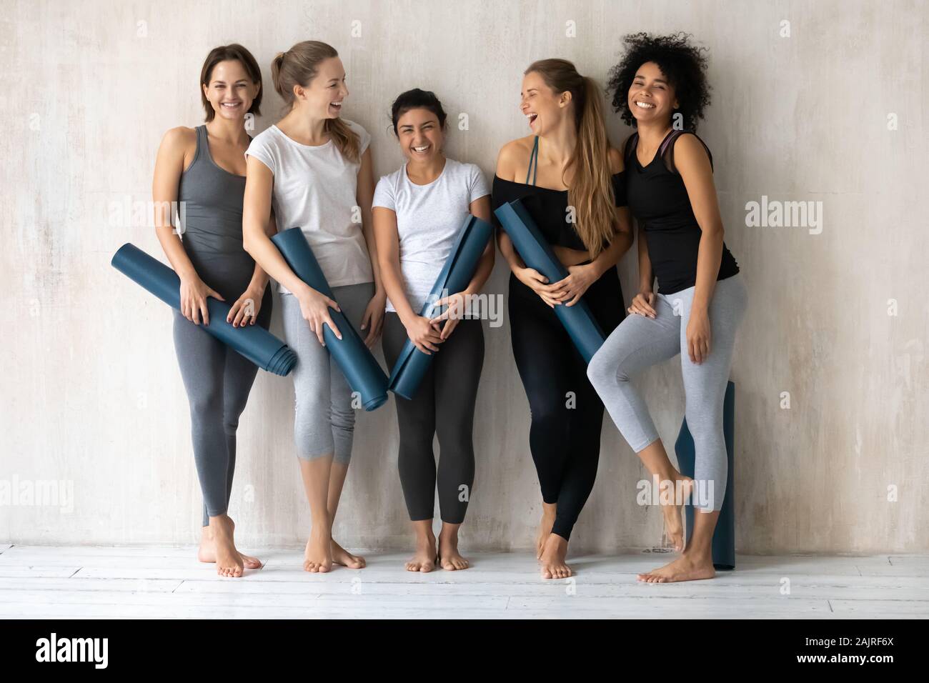 Felice diverse belle ragazze con Materassini da yoga in piedi in palestra Foto Stock