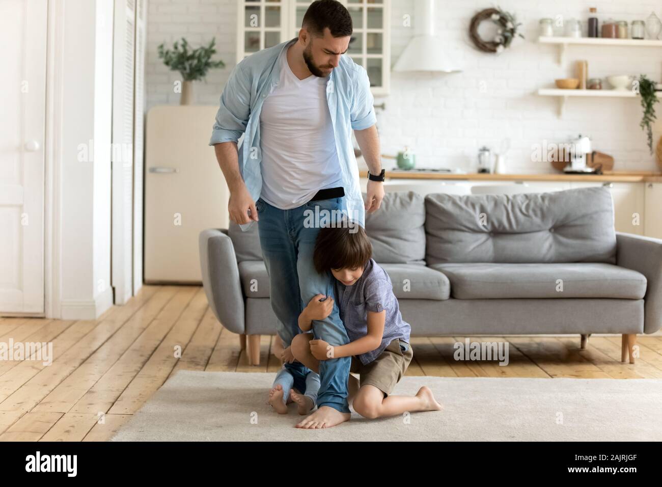 Padre lasciando mentre i suoi bambini tenere lui a non lasciar andare Foto Stock